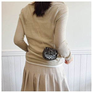 Close-up of leopard print mini saddle bag with gold chain strap on a model