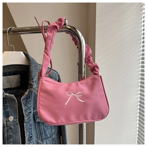 Dettaglio della borsa a spalla rosa pieghettata con fiocco bianco ricamato sul davanti
