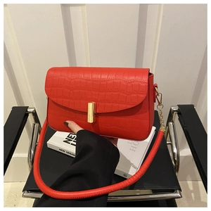 Detail of red croc-embossed texture bag with gold rectangular lock and chain strap