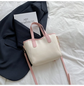Top-down view of cream and pink bucket bag on navy suit and artistic books