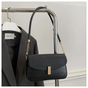 Detail of black faux crocodile skin texture and gold buckle on a chic shoulder bag