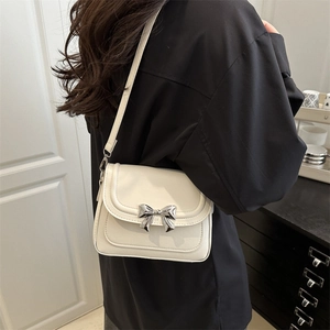 Elegant cream white crossbody bag with silver bow accent shown on model side view