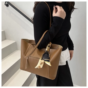 Close-up of brown leather tote bag with stylish printed silk scarf on the handle