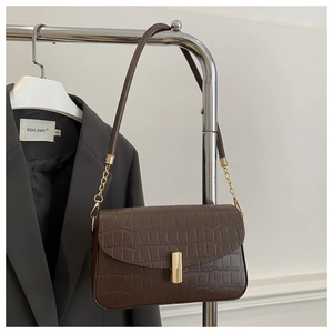 Detail of dark brown faux crocodile leather bag with gold buckle and chain strap