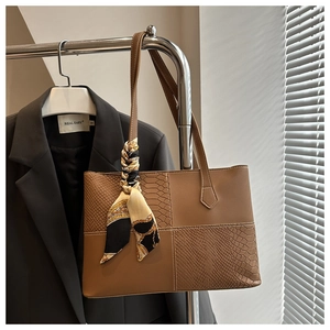Détail d'un sac cabas marron avec motif crocodile et foulard en soie décoratif sur l'anse