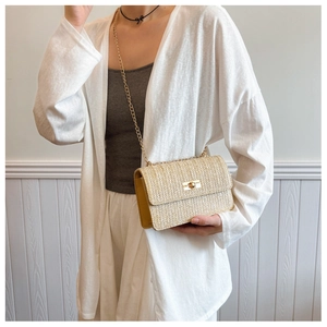 Detail of beige straw crossbody bag with gold twist lock and woven texture design
