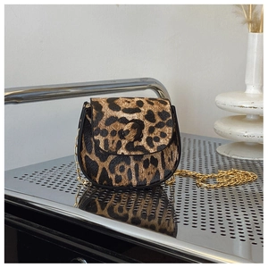 Close-up of leopard print saddle bag with faux pony hair texture and gold chain strap