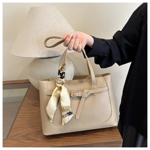 Close-up of khaki PU leather tote bag with elegant silk scarf and gold chain print details