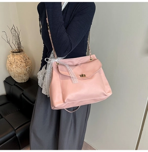Nahaufnahme einer rosa Kettenschultertasche mit goldenem Drehverschluss an einem Model