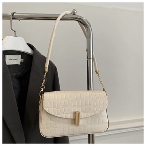 Macro view of cream croc-effect faux leather bag featuring a gold cylindrical clasp
