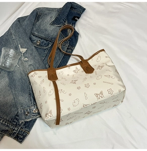 Detail of off-white tote bag with cartoon butterfly prints and slim brown handles