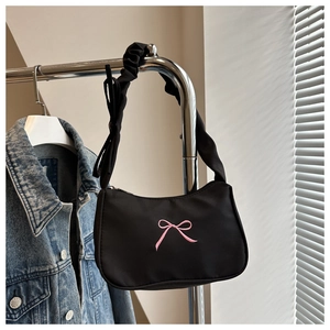 Dettaglio borsa a spalla nera con ricamo a fiocco rosa e tracolla con arricciature
