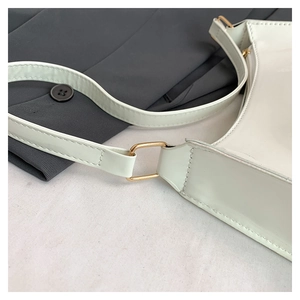 Detail of mint green patent leather bag with gold hardware buckle and fine stitching