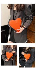 Detail der orangefarbenen Herz-Ledertasche mit gewebtem LOVE-Griff an einem Modell