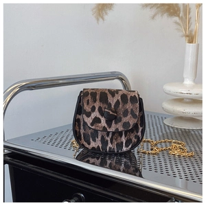 Detailed close-up of leopard print saddle bag with golden chain and button closure