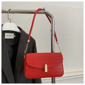 Detail of red crocodile pattern leather underarm bag with gold metal clasp on display