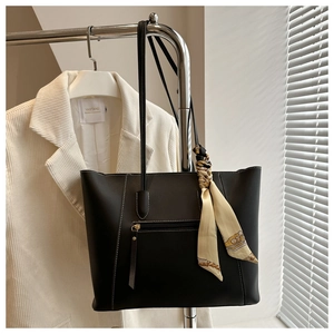 Close-up of black tote bag with white contrast stitching and decorative silk scarf detail
