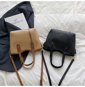 Detail of khaki and black leather tote bags with gold hardware and fashion branding