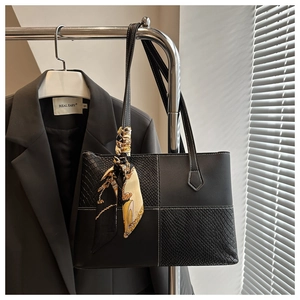 Détail d'un cabas noir avec coutures contrastées blanches et foulard en soie imprimé