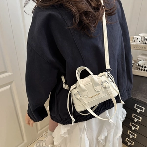 White mini drawstring crossbody bag in textured faux leather with gold fashion lettering