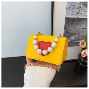 Détail du mini sac jaune avec cœur rouge, poignée en perles et bandoulière en chaîne