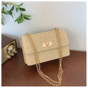 Close-up of beige woven straw handbag with gold chain strap and metallic lock clasp