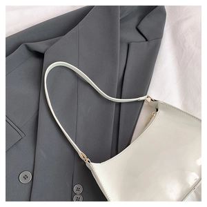 Close-up of white patent leather shoulder bag with crescent shape and glossy texture