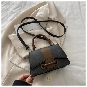 Detail of cross-body bag featuring grey fabric texture and brown leather strap accents