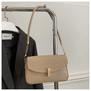 Detail of beige faux leather handbag with crocodile pattern and golden metal chain strap