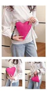 Detail der pinkfarbenen herzförmigen Clutch mit buntem LOVE-Riemen und goldenen Beschlägen