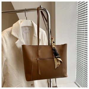 Close-up of brown faux leather tote bag with silk scarf detail and front zipper pocket