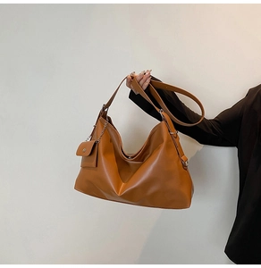 Close-up of brown PU leather tote bag with wide strap and matching chain pouch detail