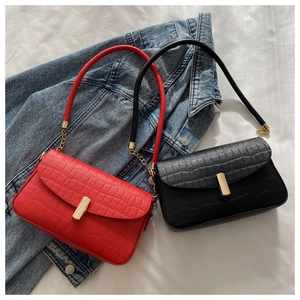 Detail of red and black crocodile embossed bags with gold metal locks on denim jacket