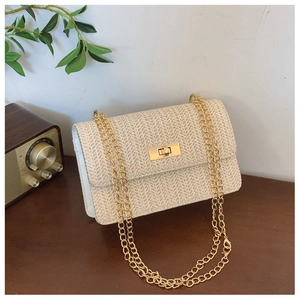 Detailed view of beige straw woven texture with golden clasp on an elegant crossbody bag