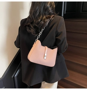 Pink cat-ear shoulder bag with metallic twist lock and chain strap on a female model