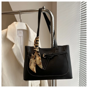 Detail of black tote bag with white contrast stitching and a silk scarf on the handle