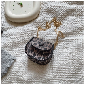 Top view of mini leopard print saddle bag with gold chain strap on white fabric