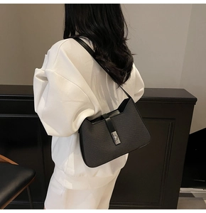 Detail of black woven fabric shoulder bag with silver turn-lock and leather strap