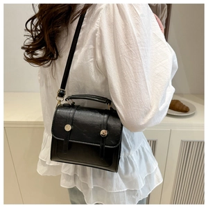 Dettaglio di una borsa a tracolla nera vintage indossata da una modella in interno sobrio