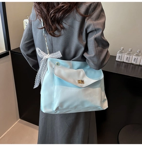 Detail der hellblauen Hobo-Tasche mit Spitzenschleife und Goldverschluss an Schulter
