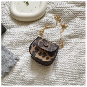 Detailed view of leopard print mini crossbody bag with gold chain strap on white fabric