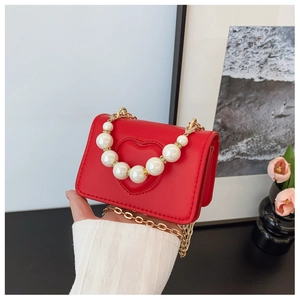Détail du mini sac carré rouge avec motif cœur gaufré et poignée en perles blanches