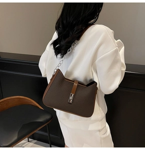 Detail of woven texture and silver chain strap on coffee brown shoulder bag