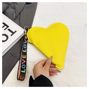 Detail der gelben herzförmigen Leder-Clutch mit einem LOVE-Logo-Stoffgriff am Taschenrand