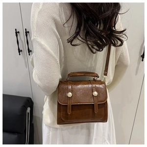 Borsa a tracolla vintage marrone con manico e fibbie dorate indossata da una modella
