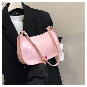 Detail of pink patent leather handbag with glossy finish and stylish shoulder strap