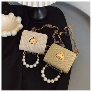 Detail of cream and brown straw-woven mini bags with golden heart clasps and pearl handles