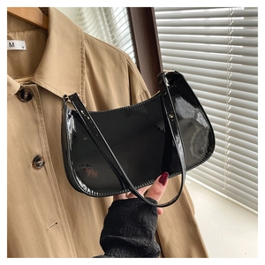 Close-up of glossy black patent leather shoulder bag with fine stitching details