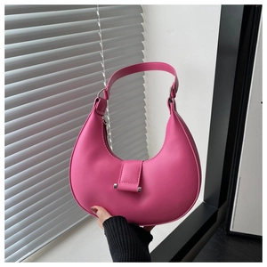 Detail of rose pink crescent bag with matte leather texture and silver metal hardware