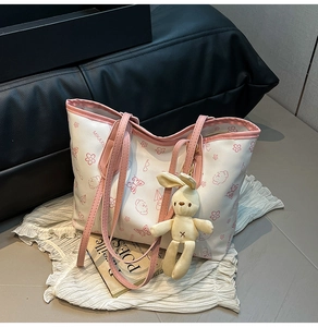Detail of pink and white tote bag with cartoon bear prints and a cute rabbit pendant